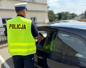 na zdjęciu policjant który rozlicza kierującego za popełnione wykroczenie. Kierujący podpisuje mandat