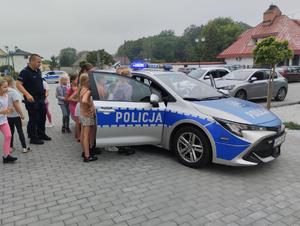 na zdjęciu policjanci pokazują dzieciom policyjny radiowóz