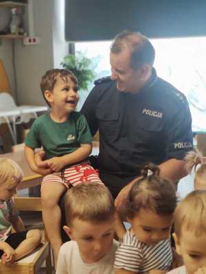 na zdjęciu dzielnicowy i dzieci się usmiechają