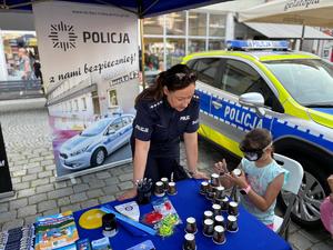 na zdjęciu policjantka w tle radiowóz i dziewczynka która bierze udział w konkursie