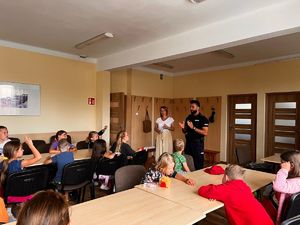 na zdjęciu policjant prowadzi prelekcje dzieci są w ławkach
