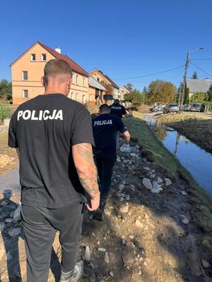 na zdjęciu policjanci idą do wyznaczonego miejsca gdzie jest potrzebna ich pomoc