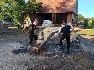 na zdjęciu 2 policjantów ładuje żwir do taczki