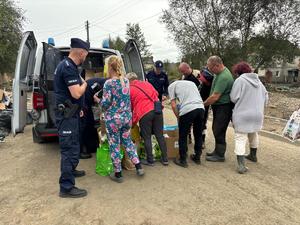 na zdjęciu policjanci rozdają potrzebne rzeczy powodzianom