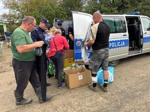 na zdjęciu policjanci rozdają potrzebne rzeczy powodzianom