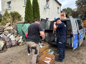 na zdjęciu policjanci rozdają potrzebne rzeczy powodzianom