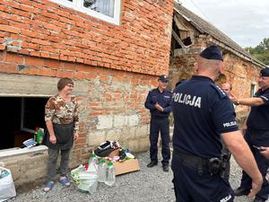 na zdjęciu policjanci rozdają potrzebne rzeczy powodzianom