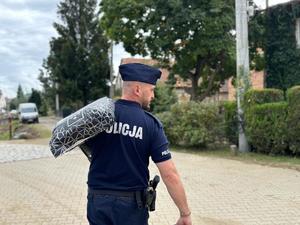 na zdjęciu policjant niesie karmę dla zwierząt