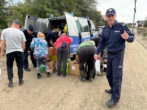 na zdjęciu policjanci rozdają potrzebne rzeczy powodzianom