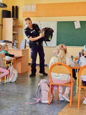 na zdjęciu policjant pokazuje plecak z odblaskami