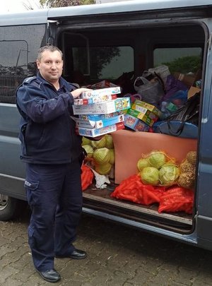 na zdjęciu policjant wkłada dary do radiowozu