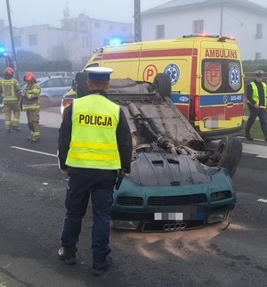 na zdjęciu wywrócony pojazd i policjant stojący tyłem