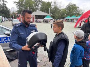 na zdjęciu policjant zakłada kask i kamizelkę dziecku