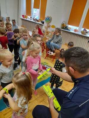 na zdjęciu policjant rozdaje odblaski