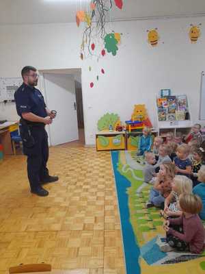 na zdjęciu policjant pokazuje dzieciom kajdanki policyjne