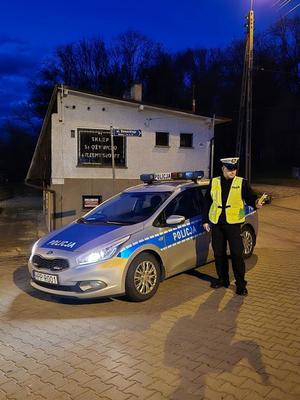 na zdjęciu policjant ruchu drogowego przy radiowozie z urządzeniem do badania trzeźwości