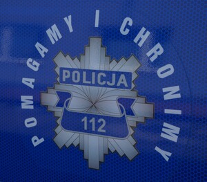 zdjęcie kolorowe przedstawiające odznakę policyjną oraz napis "pomagamy i chronimy"