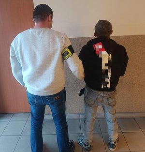 na zdjęciu kryminalny i mężczyzna zatrzymany stoją tyłem