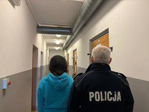 na zdjęciu policjant i zatrzymana kobieta stoją tyłem