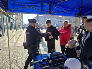 na zdjęciu policjant zakłada kamizelkę mężczyźnie