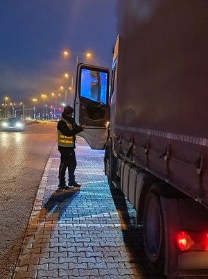 na zdjęciu policjant ruchu drogowego kontroluje ciężarówkę