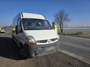 na zdjęciu policjant ruchu drogowego kontroluje białego busa