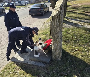 na zdjęciu policjanci kładą znicz na obelisku