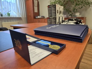 na zdjęciu na stole leży medal i akty mianowania
