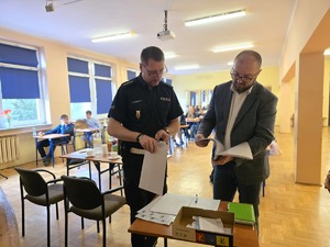 na zdjęciu dyrektor i policjant sprawdzaja testy