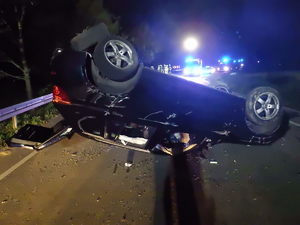 na zdjęciu pojazd który jest na dachu a z tyłu służby ratunkowe