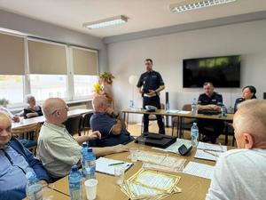 na zdjęciu policjant z ruchu drogowego opowiada o bezpieczeństwie na drodze