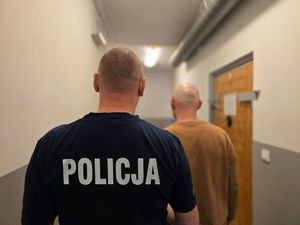 na zdjeciu policjant z zatrzymanym stoja tyłem