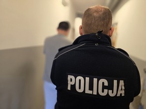 na zdjeciu zatrzymany z policjantem stoja tyłem