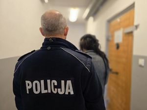 na zdjęciu zatrzymana z policjantem stoją tyłem