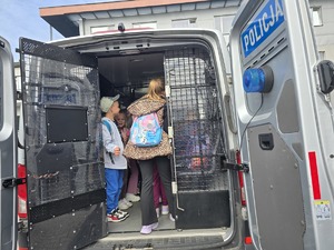 na zdjęciu dzieci siedzą w dużym radiowozie