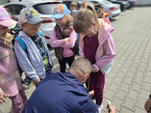 na zdjęciu policjant pokazuje dzieciom kajdanki