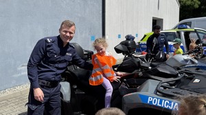 na zdjęciu policjant asekuruje przedszkolaka siedzącego na quadzie