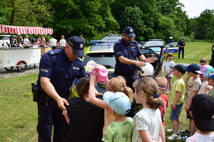 na zdjęciu policjanci przymierzają dzieciom sprzęt