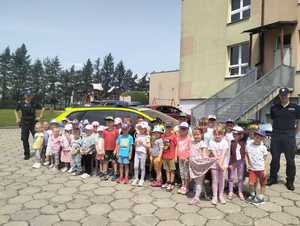 na zdjeciu policjanci z dziecmi przy radiowozie