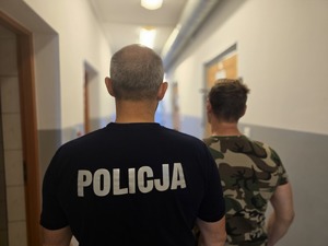 na zdjęciu zatrzymany z policjantem tyłem