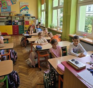 na zdjeciu dzieci w ławkach