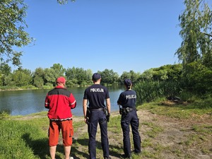 NA ZDJĘCIU DZIELNICOWY I PRZEDSTAWICIELE WOPR KONTROLUJA ZBIORNIKI WODNE