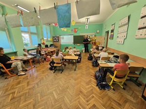 na zdjęciu policjant opowiada o bezpieczeństwie dzieci w ławkach słuchają wykładu
