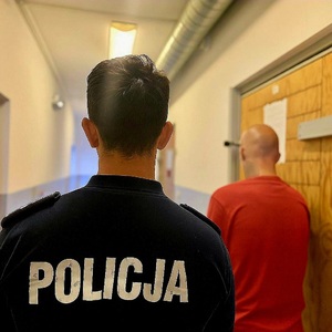 na zdjeciu zatrzymany tylem i policjant tyłem