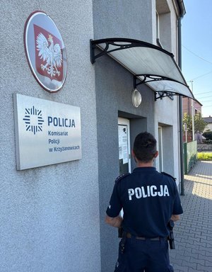 na zdjęciu policjant stoi tyłem przy komisariacie w Krzyżanowicach
