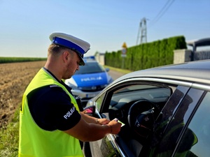 na zdjęciu policjant wypisuje mandat