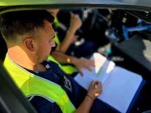 na zdjęciu policjant pisze w notatniku służbowym
