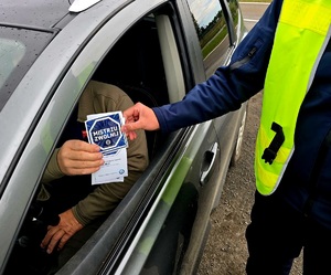 na zdjęciu policjant daje naklejkę kierującemu