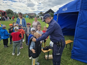 na zdjęciu policjant przymierza dzieciom mundur ochronny