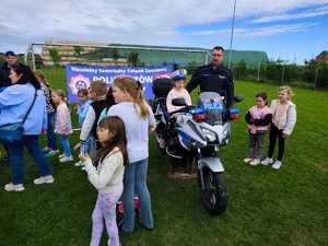 na zdjeciu policjant ruchu drogowego i dzieci przy motocyklu